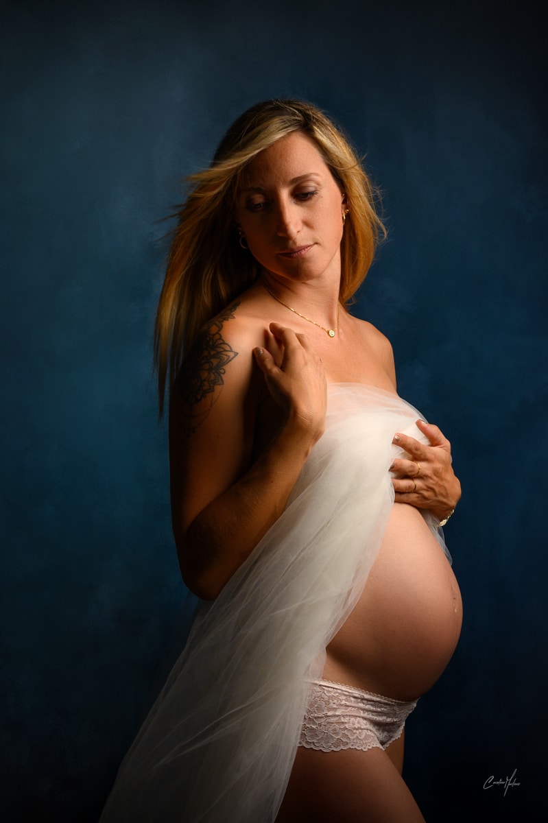 photo de grossesse d'une femme dans son voile de mariée