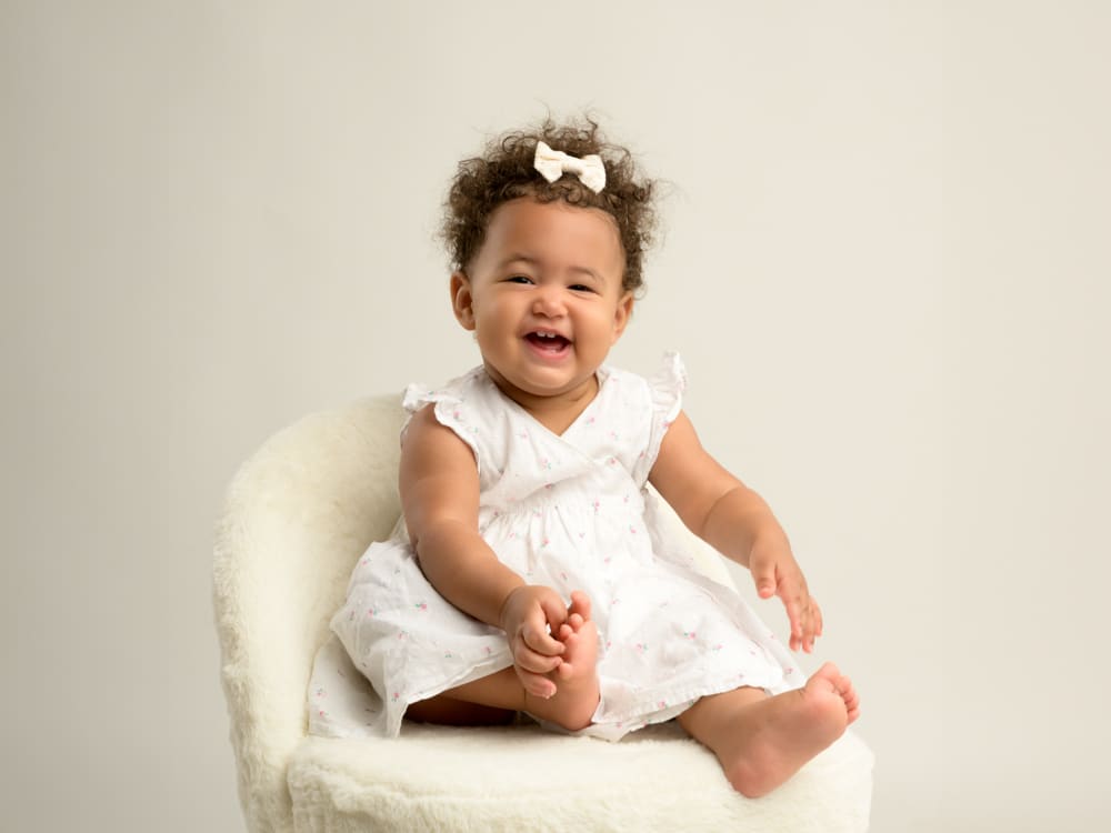 photo d'une petite fille souriante sur une chaise en studio photo