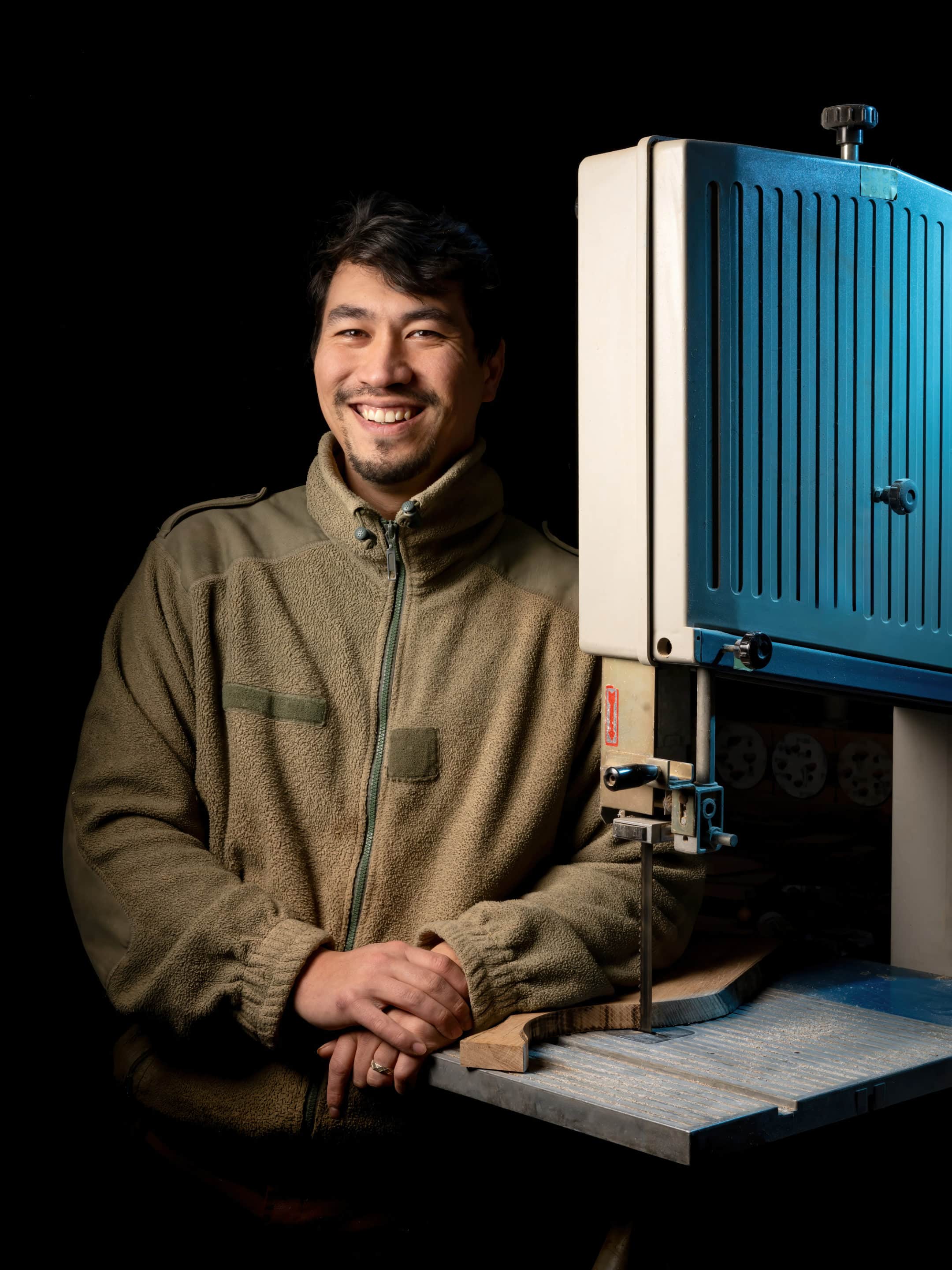 portrait d'un artisan menuisier posant à coté de son outil de travail