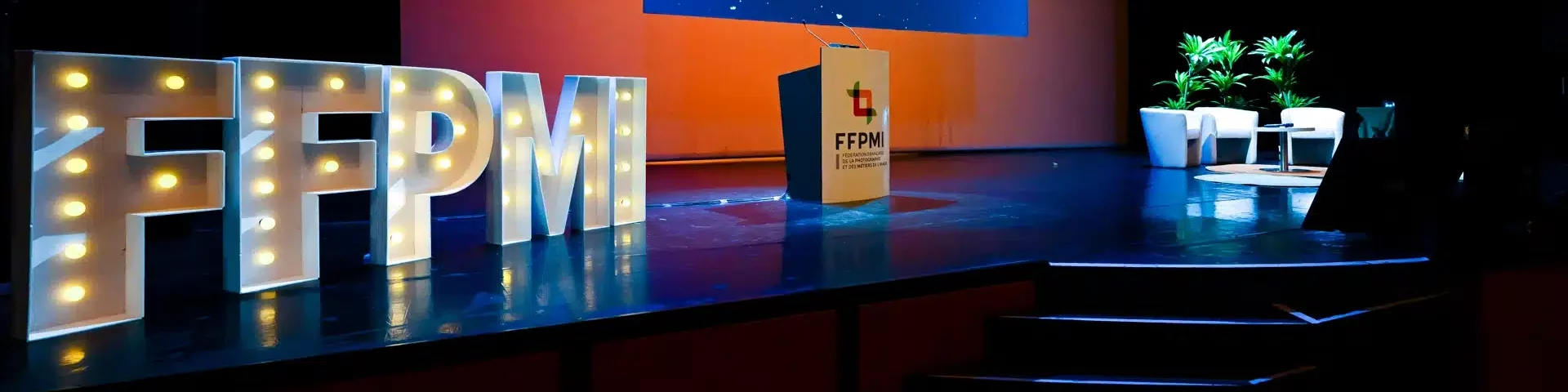 Vue rapprochée des lettres FFPMI en lumière sur scène