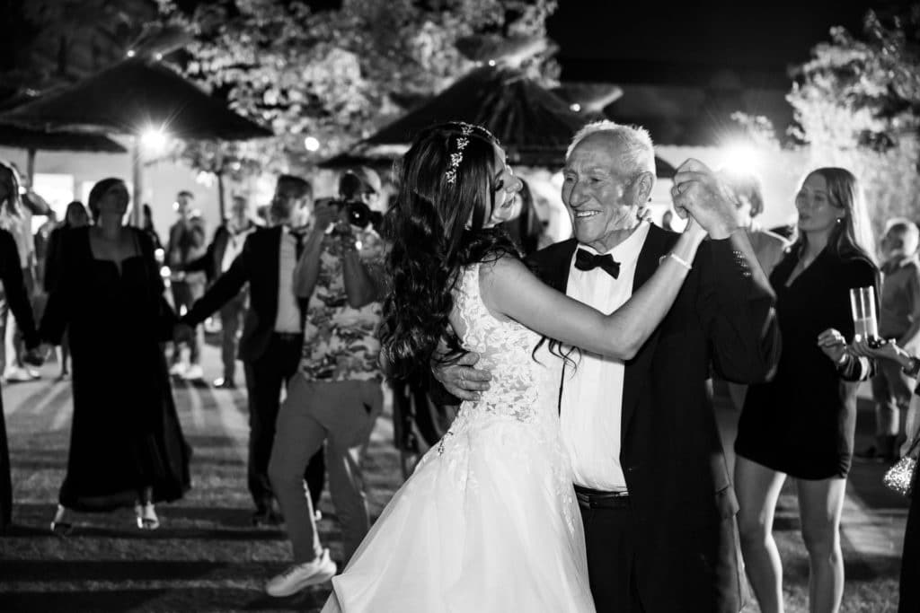 Mariée dansant avec un proche lors de la soirée de mariage, sourire partagé et ambiance chaleureuse en plein air